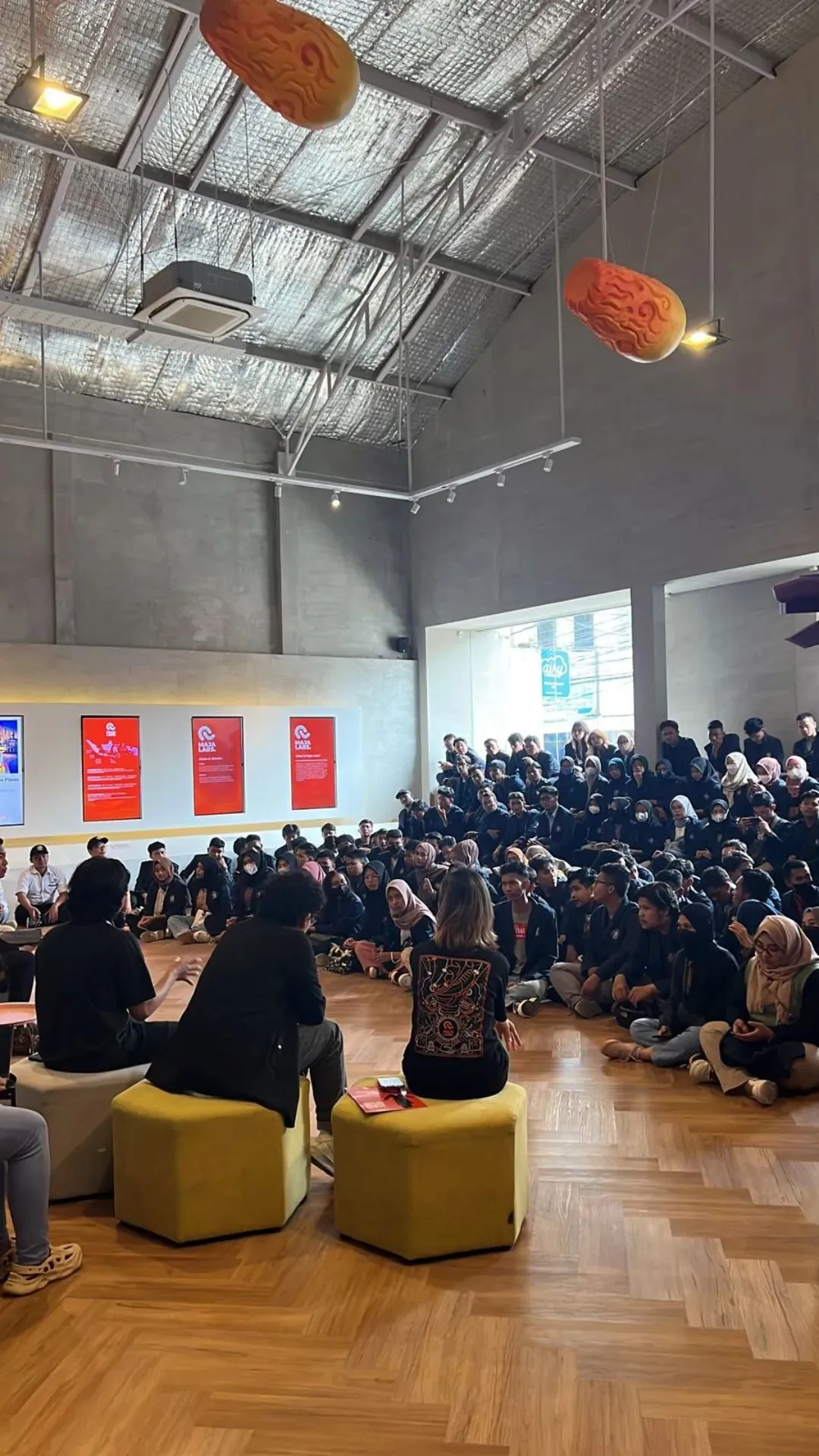 Anggota tim Native Productions berbicara di depan ruangan penuh mahasiswa.